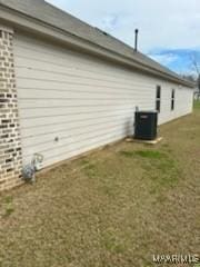 view of side of property with a yard and central air condition unit