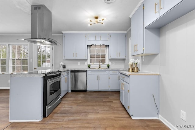 kitchen featuring island range hood, stainless steel appliances, a sink, light countertops, and crown molding