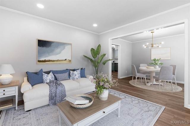 living area with baseboards, ornamental molding, a chandelier, and wood finished floors