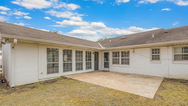 back of property featuring a yard, a patio, brick siding, and a shingled roof