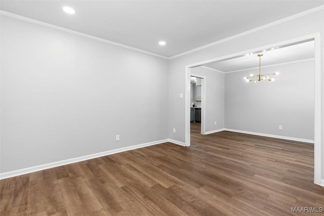 spare room with baseboards, dark wood-type flooring, an inviting chandelier, crown molding, and recessed lighting