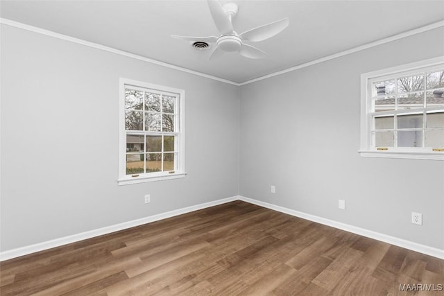 empty room with plenty of natural light, crown molding, and wood finished floors