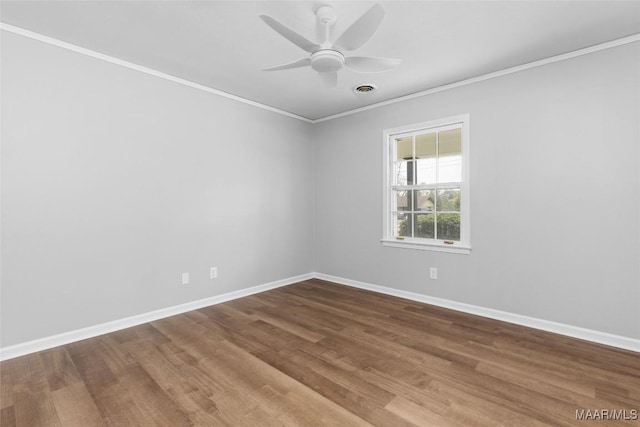 spare room featuring a ceiling fan, baseboards, crown molding, and wood finished floors