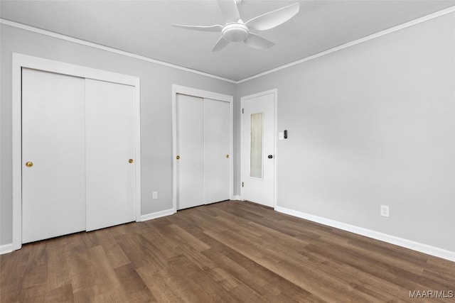 unfurnished bedroom with multiple closets, crown molding, baseboards, and wood finished floors