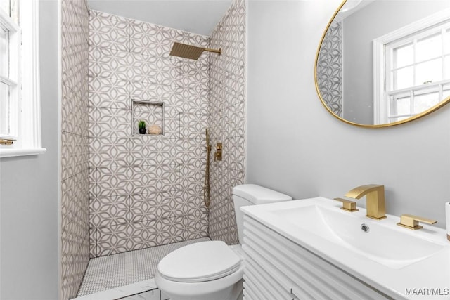 bathroom with a tile shower, a sink, and toilet