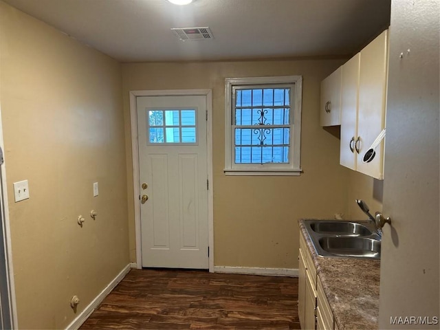 doorway featuring baseboards, visible vents, dark wood-type flooring, and a sink