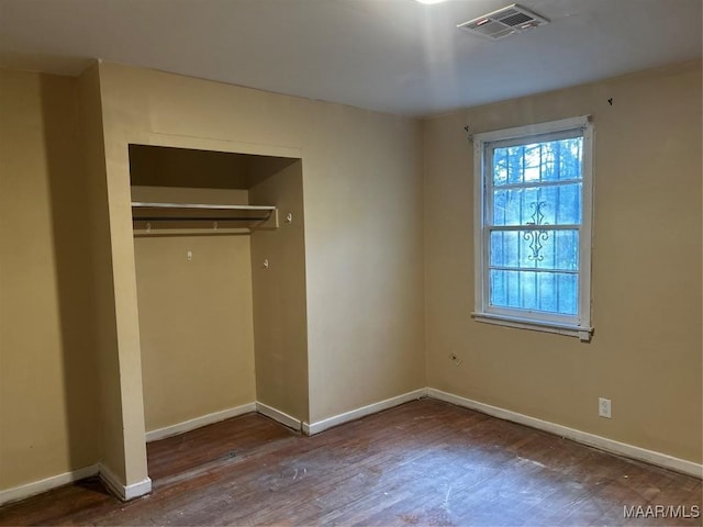 unfurnished bedroom featuring baseboards, visible vents, dark wood finished floors, and a closet