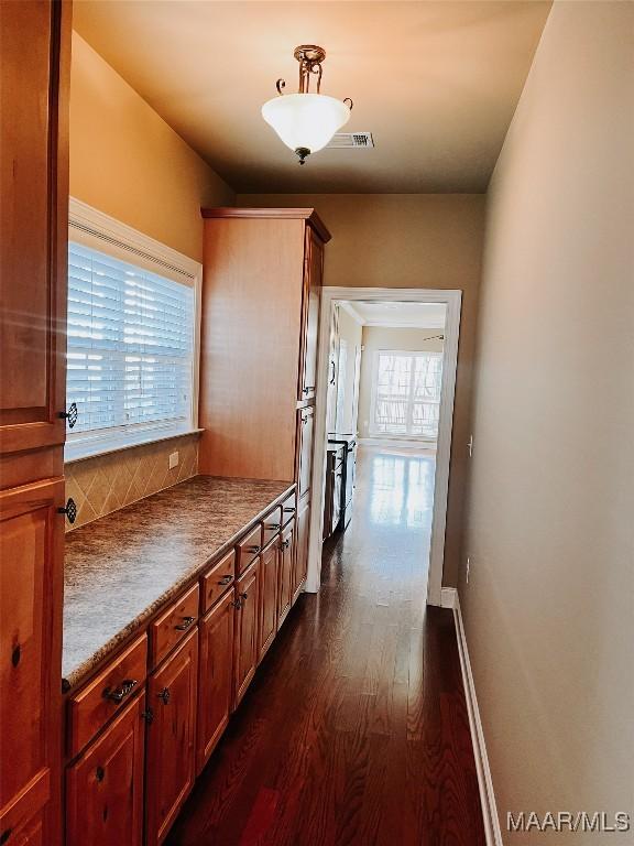 corridor featuring visible vents, baseboards, and dark wood-type flooring