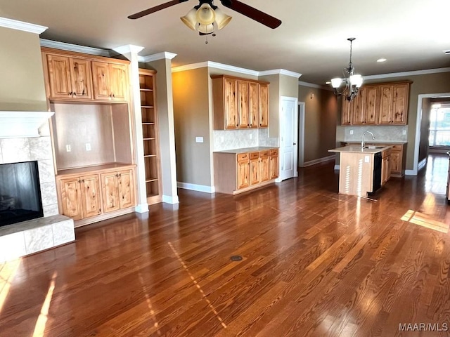 kitchen featuring dark wood-style floors, a premium fireplace, brown cabinets, light countertops, and a sink