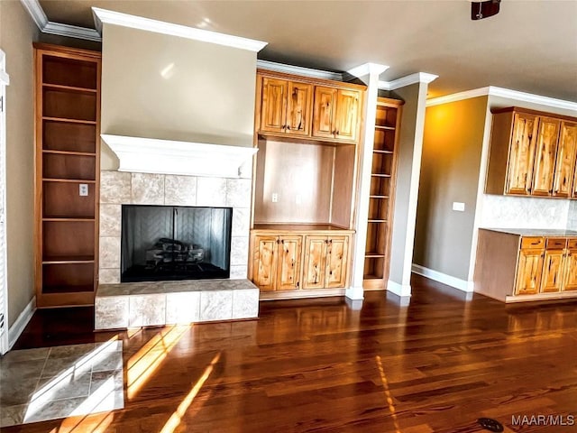 unfurnished living room featuring crown molding, a tile fireplace, dark wood finished floors, and baseboards