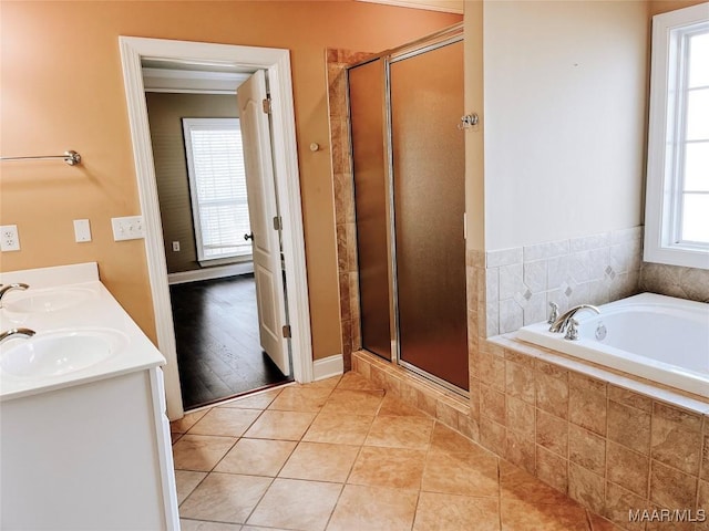 full bath featuring a stall shower, tile patterned flooring, a garden tub, and a sink