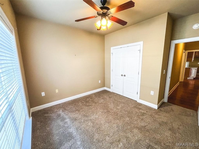 unfurnished bedroom featuring carpet floors, ceiling fan, baseboards, and a closet