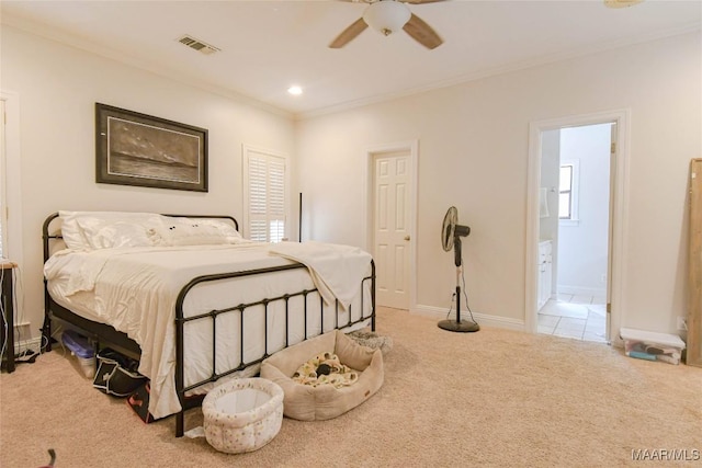 bedroom with ensuite bathroom, light carpet, visible vents, baseboards, and ornamental molding