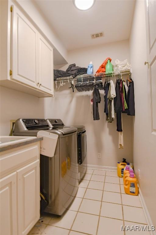 laundry room featuring cabinet space, light tile patterned floors, baseboards, visible vents, and washing machine and clothes dryer