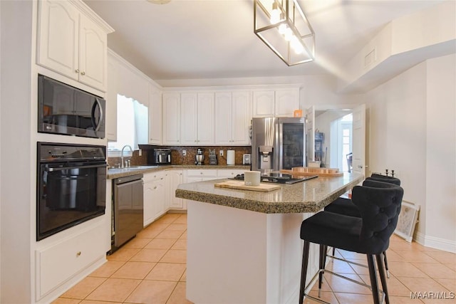 kitchen featuring stainless steel fridge, dishwasher, a kitchen breakfast bar, oven, and white cabinetry