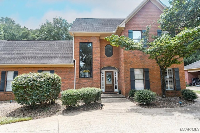 view of front of property featuring brick siding and a shingled roof