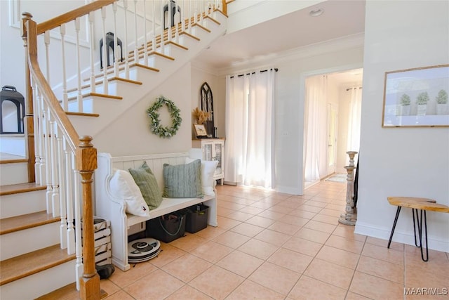 stairway featuring baseboards, tile patterned flooring, and crown molding