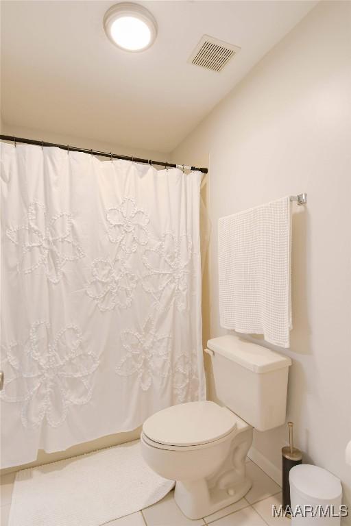 full bathroom featuring a shower with shower curtain, tile patterned flooring, visible vents, and toilet