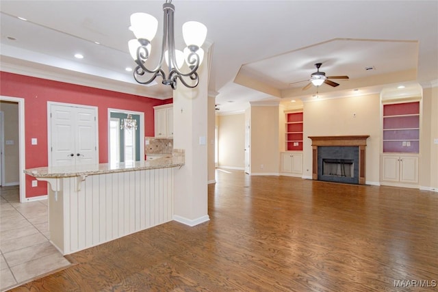 kitchen with a peninsula, a fireplace, open floor plan, hanging light fixtures, and a kitchen bar