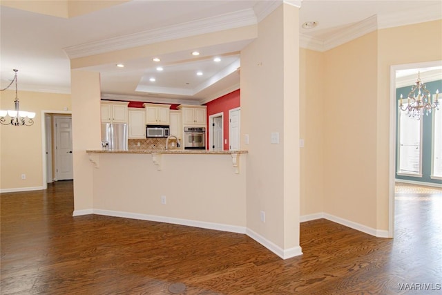 kitchen with a breakfast bar area, a peninsula, light stone countertops, stainless steel appliances, and a notable chandelier