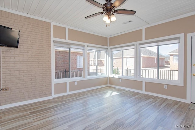 unfurnished sunroom featuring a ceiling fan, visible vents, and a wealth of natural light