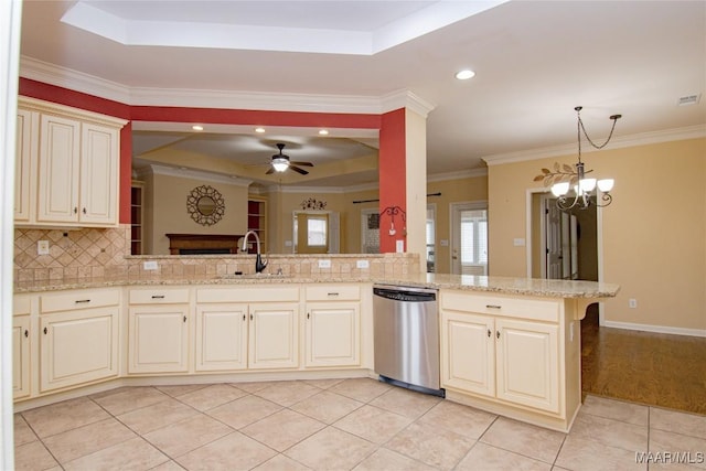 kitchen featuring a raised ceiling, a peninsula, light stone countertops, stainless steel dishwasher, and a sink