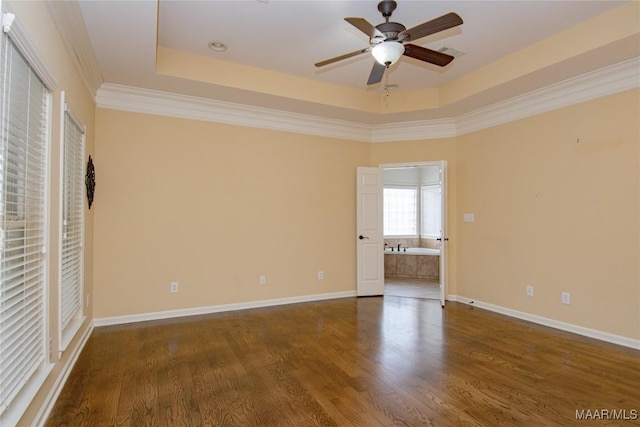 unfurnished room with a tray ceiling, dark wood finished floors, baseboards, and ceiling fan