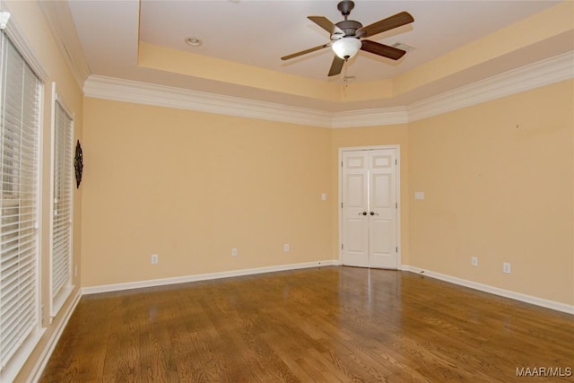 unfurnished room featuring ceiling fan, wood finished floors, a raised ceiling, and baseboards