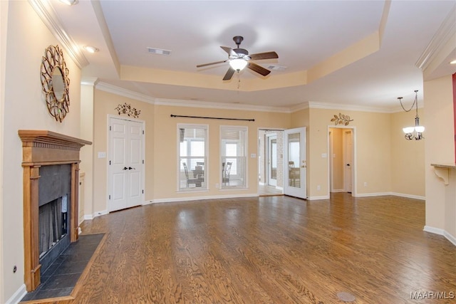 unfurnished living room with ceiling fan with notable chandelier, dark wood-type flooring, a fireplace, visible vents, and a tray ceiling