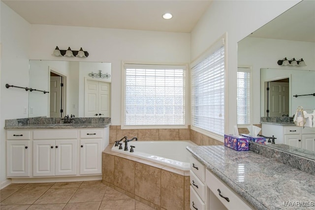 bathroom featuring tile patterned flooring, two vanities, a sink, and a garden tub