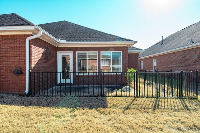 rear view of property with a shingled roof, fence, a lawn, and brick siding