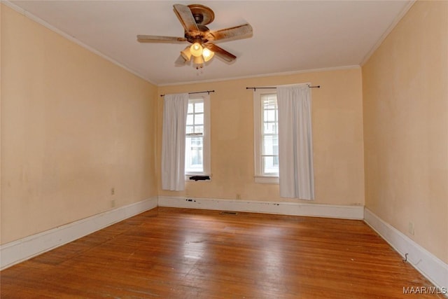 spare room with baseboards, wood finished floors, a ceiling fan, and crown molding