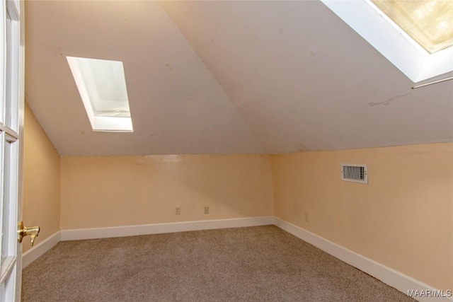 additional living space featuring baseboards, lofted ceiling with skylight, visible vents, and light colored carpet