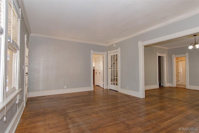 unfurnished room featuring baseboards, dark wood-type flooring, ornamental molding, and an inviting chandelier