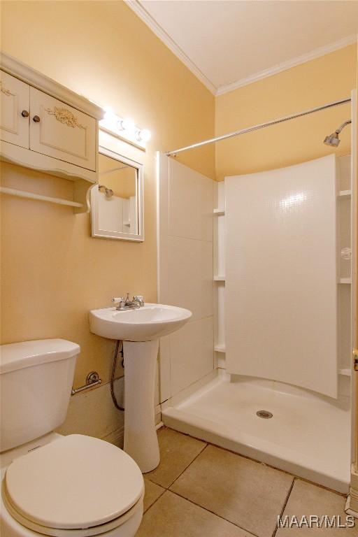 bathroom with a shower, crown molding, toilet, a sink, and tile patterned flooring