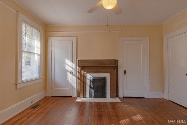 unfurnished living room featuring visible vents, a fireplace with flush hearth, ornamental molding, wood finished floors, and baseboards