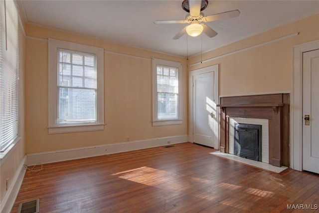 unfurnished living room with a fireplace, wood finished floors, a ceiling fan, visible vents, and crown molding