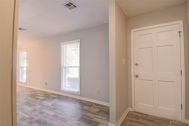 entryway featuring baseboards, a textured ceiling, visible vents, and wood finished floors