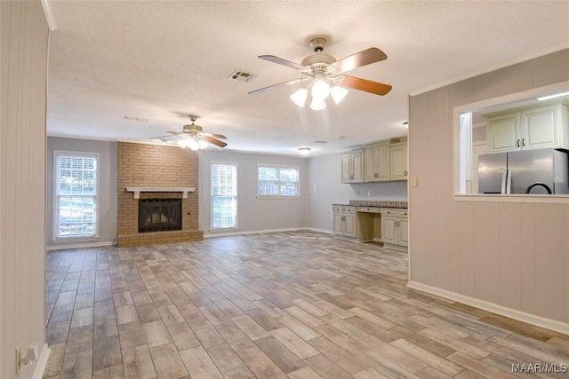 unfurnished living room with light wood-style floors, a textured ceiling, visible vents, and a wealth of natural light