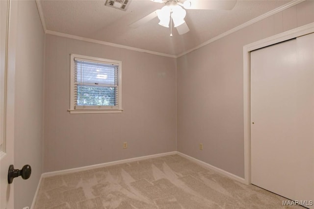 unfurnished bedroom featuring crown molding, a closet, light colored carpet, visible vents, and baseboards