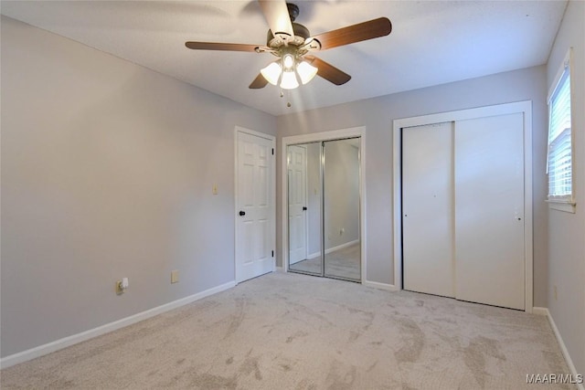 unfurnished bedroom with a ceiling fan, light colored carpet, baseboards, and two closets