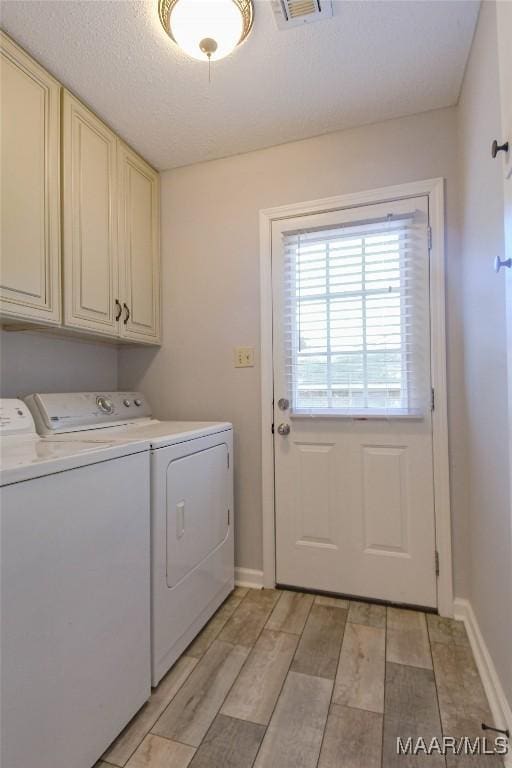 washroom with washing machine and dryer, cabinet space, baseboards, and wood tiled floor