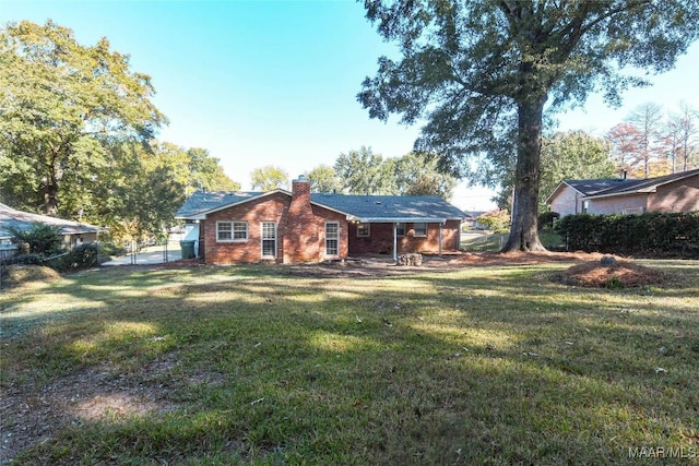 rear view of house with brick siding, a chimney, fence, and a lawn