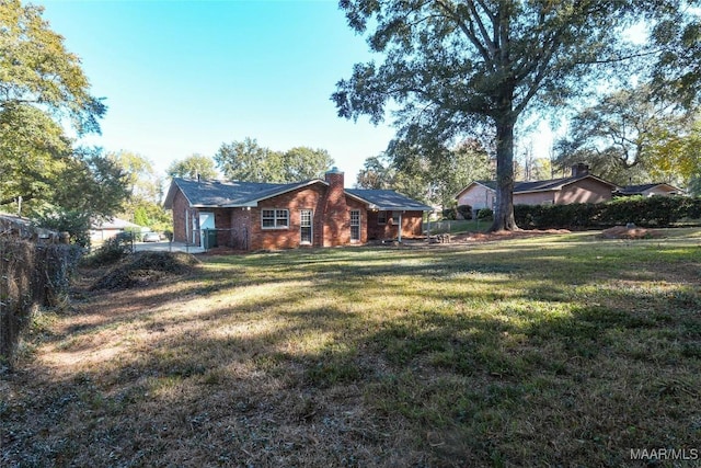 exterior space featuring a yard, brick siding, a chimney, and fence