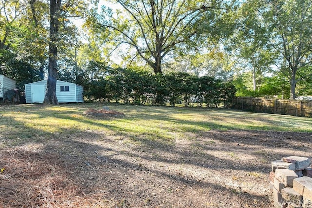 view of yard with a storage shed, fence, and an outdoor structure