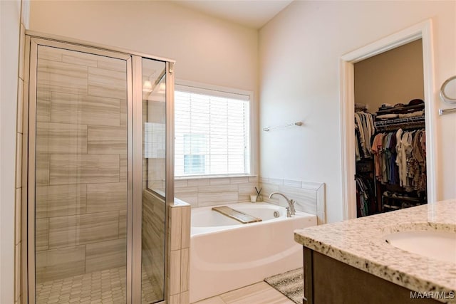 full bath featuring a stall shower, a spacious closet, a bath, and vanity