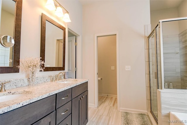 bathroom featuring double vanity, a stall shower, and a sink