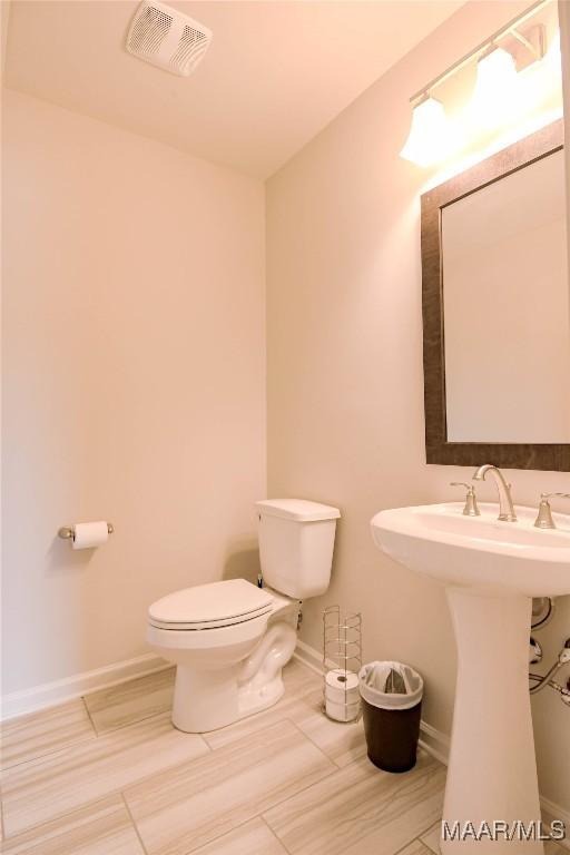 bathroom featuring baseboards, visible vents, a sink, and toilet