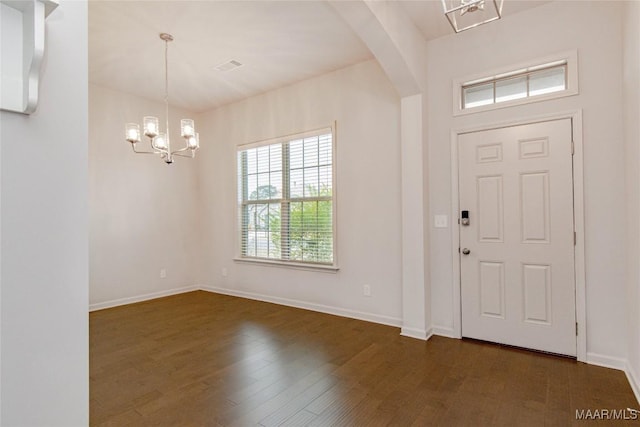 foyer entrance featuring dark wood-style floors, baseboards, arched walkways, and a notable chandelier