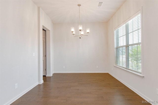 empty room with baseboards, dark wood finished floors, visible vents, and a notable chandelier